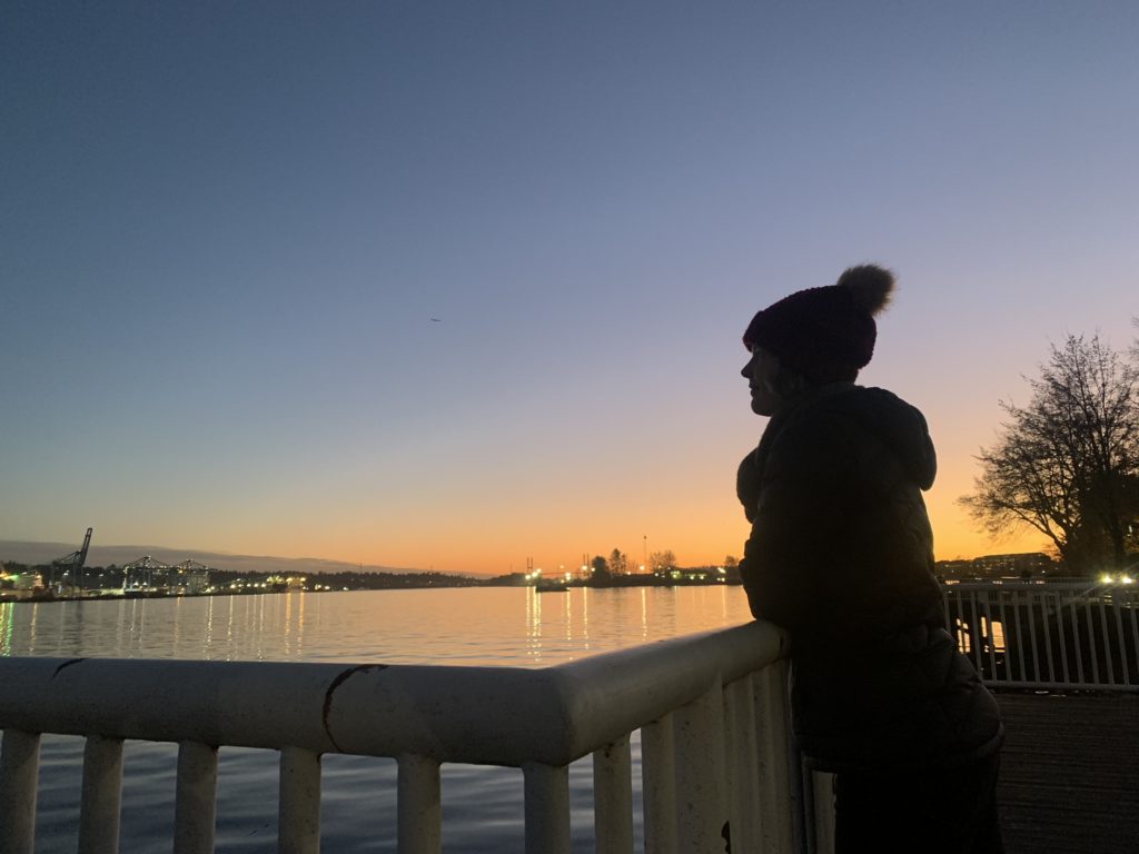Women looks out to the Fraser River with sunset in behind