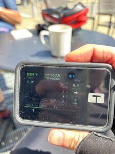 A close up of the Tandem t:slim insulin pump with a cup of steaming matcha tea on the table in the background next to a bicycle helmet.