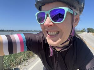 Katie taking a selfie while riding her bike with the Fraser River next to her